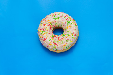 Fototapeta na wymiar donut with colored sugar sprinkles on blue background