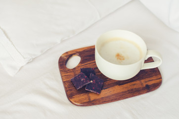 Cup of cappuccino on the bed