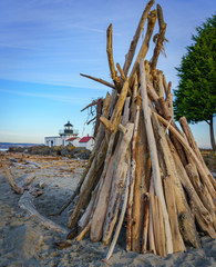 Fototapeta na wymiar driftwood on the beach with lighthouse behind it at Point No Point