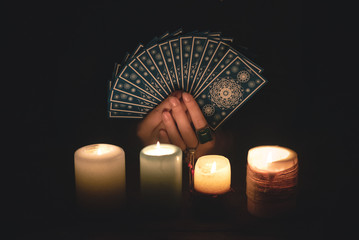 Fortune teller reading a future by tarot cards in the light of candle concept.
