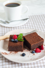 dark chocolate brownie pieces decorated with mint and berries on a white plate classical  recipe 
