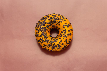 orange donut with black powder on brown background, top view