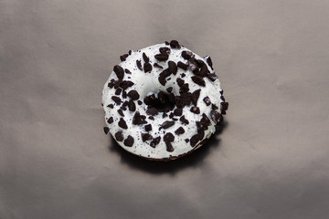 white donut dusted with cookies on black background, top view