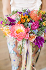 Woman holds peonies, roses and other colored flowers in her hands. Florist training workshop on creating flower bouquets. Floristics Studio.