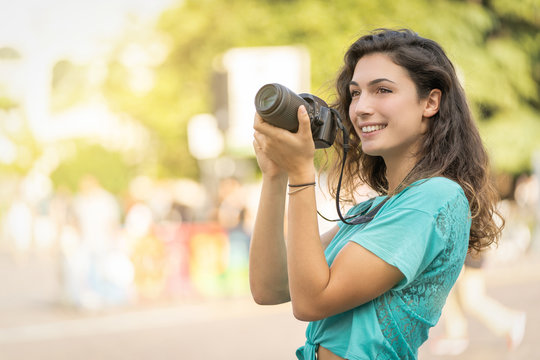 Smiling girl in an Italian city with a camera in her hand. Tourist or professional photographer