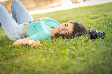 Photographer girl lying on the grass happy and smiling, relaxing