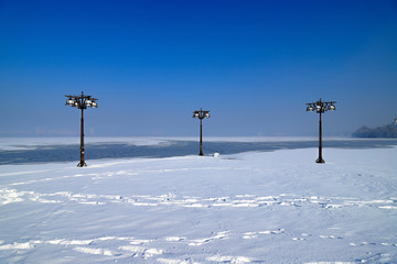 Blue winter landscape of a snowy river and embankment with vintage metal lanterns, Dnepropetrovsk,...