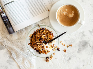 Healthy breakfast. Granola, muesli with pumpkin seeds, honey, yogurt in a glass bowl with a cup of coffee on white background. Breakfast of a modern girl. Close up, copy space.. top view