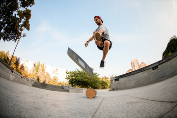 Fish-eye shot from below boy making trick on the balance board on the concrete border