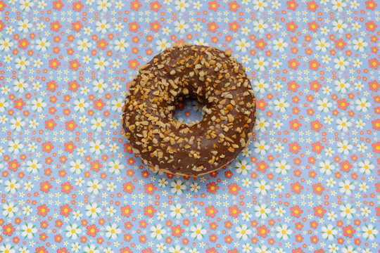 Donut On Blue With Red Flowers Background, Top View