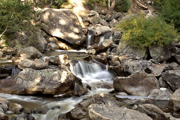 Water flowing across mountain rocky stream in early fall