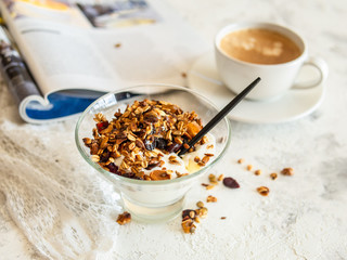 Healthy breakfast. Granola, muesli with pumpkin seeds, honey, yogurt in a glass bowl with a cup of coffee on white background. Breakfast of a modern girl. Close up, copy space.