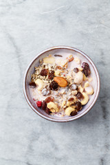 Bowl of granola with yogurt, nuts, raisins, cranberries and chia seeds. Concept for a tasty and healthy meal. Stone background. Top view. Copy space.
