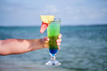 Woman holding cocktail on the beach overlooking ocean in Fiji