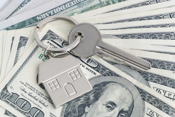 Home keys and a small house on currencies dollar background. The concept of renting or selling a...