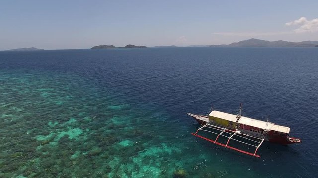 Flying a tourist camera traveler personal solo drone over a shallow coral reef ecosystem for snorkeling and diving in clear water, to the ocean sea blue drop off 