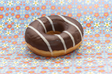 donut on purple with red flowers background, close up view