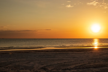 Sunset scene at Fort Myers Beach, FL, with bright orange color, sandpiper silhouette and reflection, and seagulls