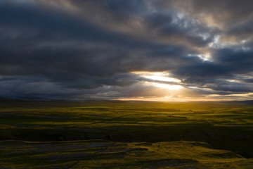 A sunrise produces shafts of light that trace across the landscape of Malham, in the Yorkshire Dales, UKf 