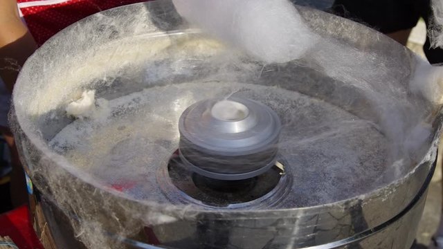 Spinning white cotton candy (candy floss) at a fair. Closeup shot of machine head. Realtime