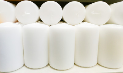 White Indoor candles in a candle store. Candles for sale in interior decorating store. Variety of different candles in shop. Discounts and sales. Candles for romantix event or holidays