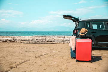 Black large car with an open luggage carrier parked on the beach. Sea landscape and free space for your product or text. Summer and sunny warm day. Copy space.