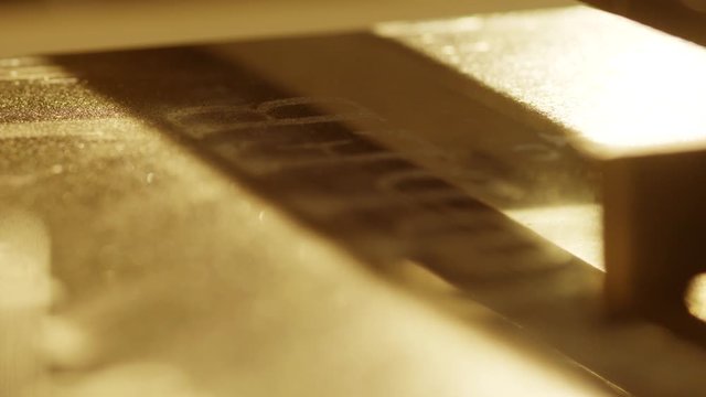 Macro view of automated carving machine working and engraving letters and patterns on surface of dark granite block dedicated for memorial stones or headstone.