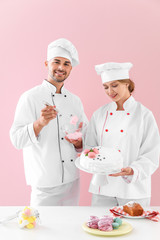 Young confectioners with tasty desserts against color background