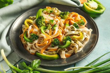 Plate with tasty pasta and vegetables on table