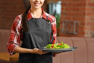 Young waitress with salad in restaurant