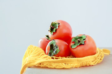 Ripe persimmons on table against light background