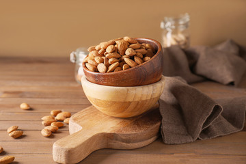 Bowls with tasty almonds on wooden table