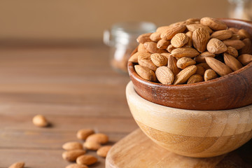 Bowls with tasty almonds on wooden table, closeup