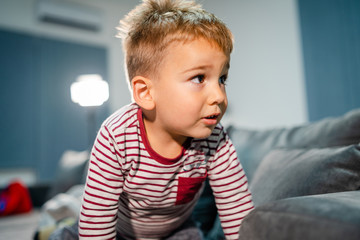 Three years old boy small little kid child playing on the bed having fun laying playful at home crawling