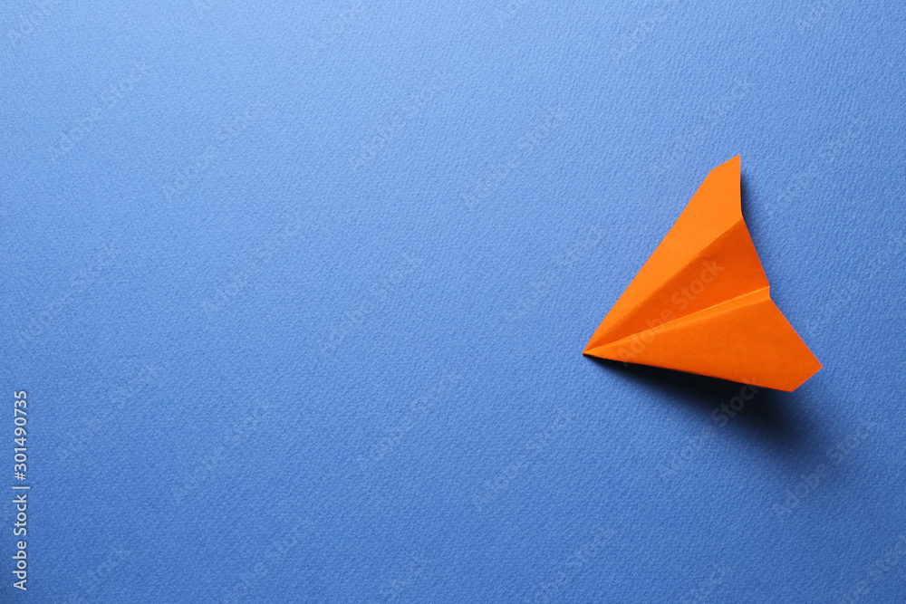 Wall mural Orange paper plane on blue background