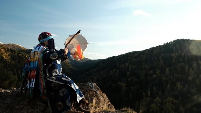 The old wizard knocks on the drum and communicates with the spirits of the forest sitting on the top of the mountain.