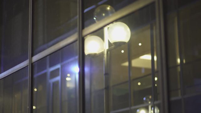 Spot lights through Skyscrapers with glass windows reflection at business district in Paris at night, slow steadicam movements, Reflections. Futuristic modern building with lights. Changing focus. 4K.