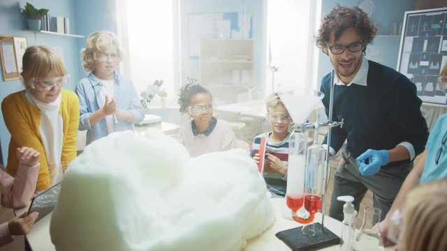 Elementary School Chemistry Classroom: Enthusiastic Teacher Teaches Diverse Group of Children Shows Science Reaction Experiment by Mixing Chemicals in Beaker so they Shoot Foam (Elephant Toothpaste)