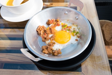 Vietnamese style fried egg in metal pan with bread and orange juice