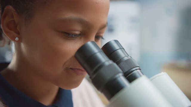 Portrait of Smart Little Schoolgirl Looking Under the Microscope. In Elementary School Classroom Cute Girl Uses Microscope. STEM (science, technology, engineering and mathematics) Education Program
