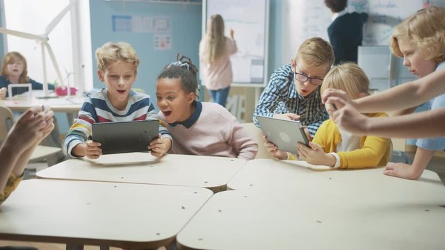 Elementary School Computer Science Class: Children Use Digital Tablet Computers and Smartphones with Augmented Reality Software, They’re Excited, Full of Wonder. Children in STEM, Playing and Learning