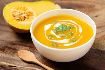 Butternut squash soup with pumpkin seed and fresh butternut squash on wooden background - obrazy, fototapety, plakaty