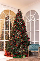 Tall Christmas tree decorated with red balls, stars, illuminations, gifts lie below