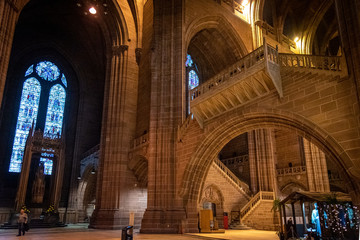 Fototapeta premium LIVERPOOL, ENGLAND, DECEMBER 27, 2018: People walking along the entrance hall of the Church of England Anglican Cathedral of the Diocese of Liverpool with a christmas tree aside during holidays.