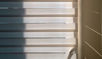 Horizontal fabric textile blinds in the interior of a living room. Illuminated by sunlight.