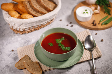 Beetroot soup with parsley in a plate, closeup. Tasty and hearty dinner. Borsch with vegetables on a gray background.