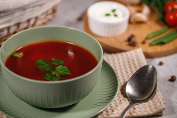 Beetroot soup with parsley in a plate, closeup. Tasty and hearty dinner. Borsch with vegetables on a gray background.