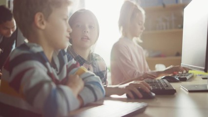 Elementary School Computer Science Classroom: Portrait of Smart Girl and Boy Talking while using Personal Computer, Learning Informatics, Internet Safety, Programming Language for Software Coding