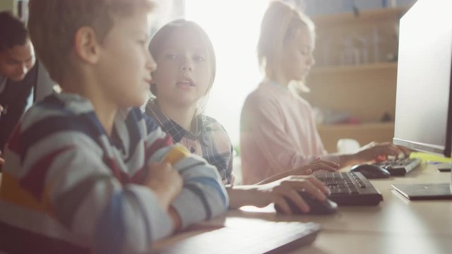 Elementary School Computer Science Classroom: Portrait of Smart Girl and Boy Talking while using Personal Computer, Learning Informatics, Internet Safety, Programming Language for Software Coding
