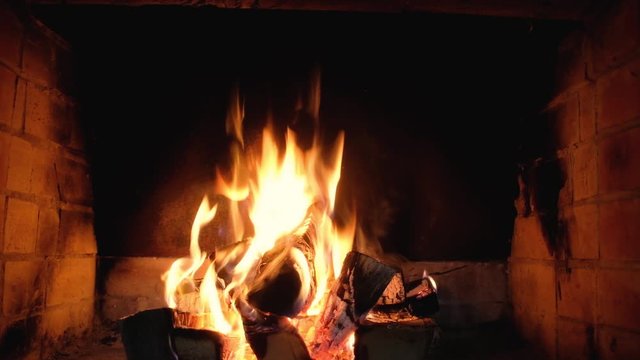 flames of the fire burn in the brick home fireplace. cozy Weekend. Warm in the house. Flames and ashes. Rest and relaxation in front of the fireplace in the evening.